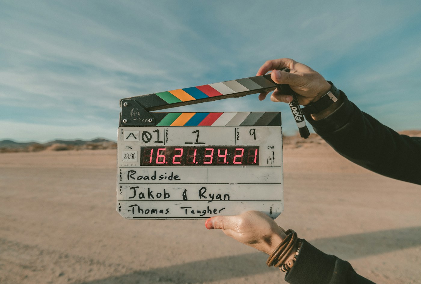 A filmmaker holding a clapperboard on an outdoor film set